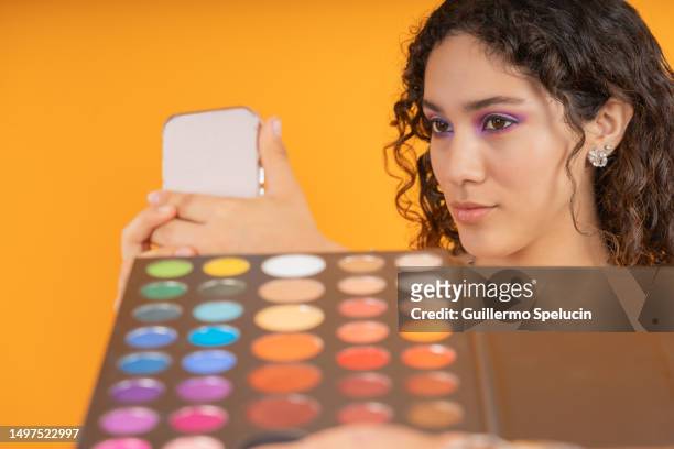 woman using a mobile phone to look at her make-up - pride gradient stock pictures, royalty-free photos & images