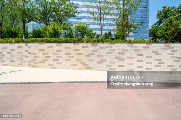 empty road and background wall covered with green plants in front of the modern office building - mittag stock-fotos und bilder