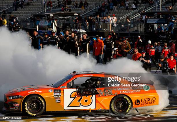 Aric Almirola, driver of the Michael Roberts Construction Ford, celebrates with a burnout after winning the NASCAR Xfinity Series DoorDash 250 at...
