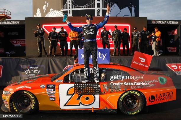 Aric Almirola, driver of the Michael Roberts Construction Ford, celebrates in victory lane after winning the NASCAR Xfinity Series DoorDash 250 at...