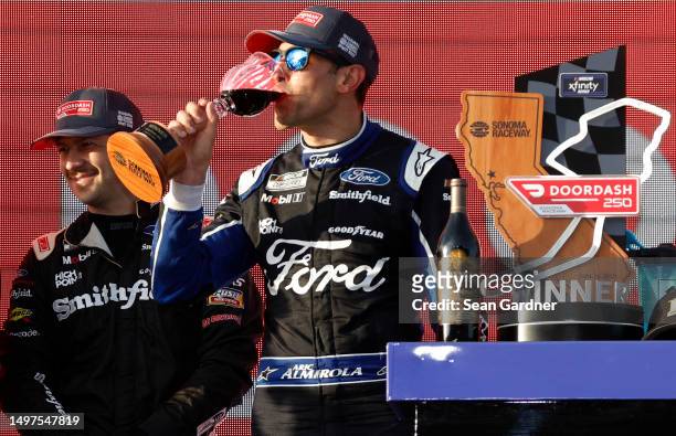 Aric Almirola, driver of the Michael Roberts Construction Ford, drinks wine in victory lane after winning the NASCAR Xfinity Series DoorDash 250 at...