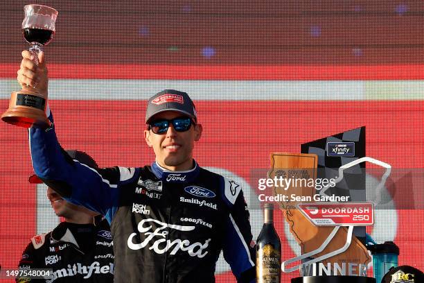 Aric Almirola, driver of the Michael Roberts Construction Ford, celebrates with wine in victory lane after winning the NASCAR Xfinity Series DoorDash...