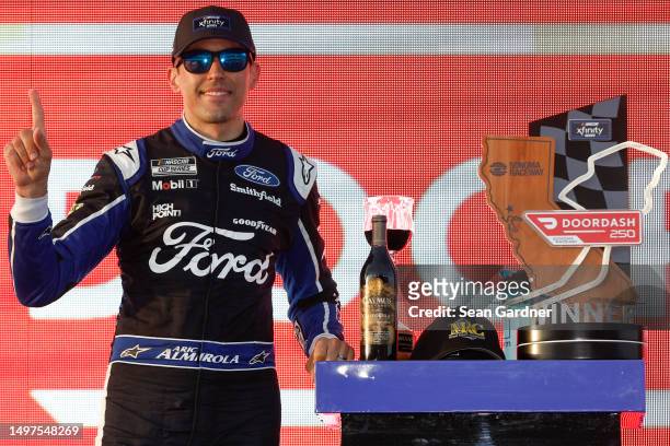 Aric Almirola, driver of the Michael Roberts Construction Ford, celebrates in victory lane after winning the NASCAR Xfinity Series DoorDash 250 at...