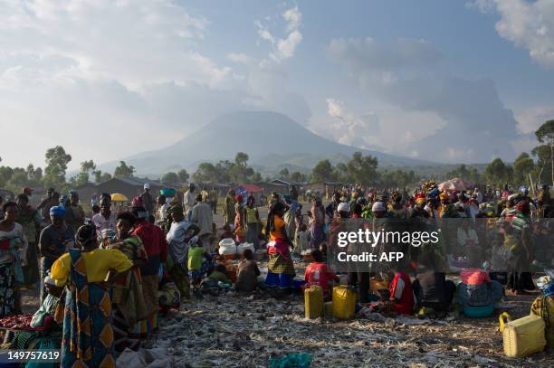 Congolese gather on the roadside at an impromptu site for the displaced in Kanyarucinya on the outskirts of Goma backdropped by the Nyiragongo...