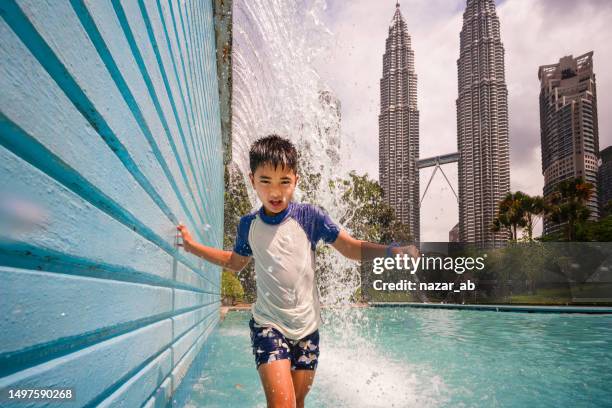 children take a bath in the fountain. - petronas towers stock pictures, royalty-free photos & images