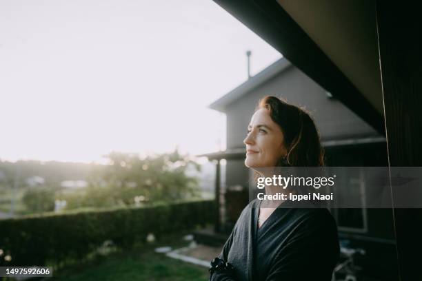 woman pondering in patio at sunset - white asian female stock pictures, royalty-free photos & images