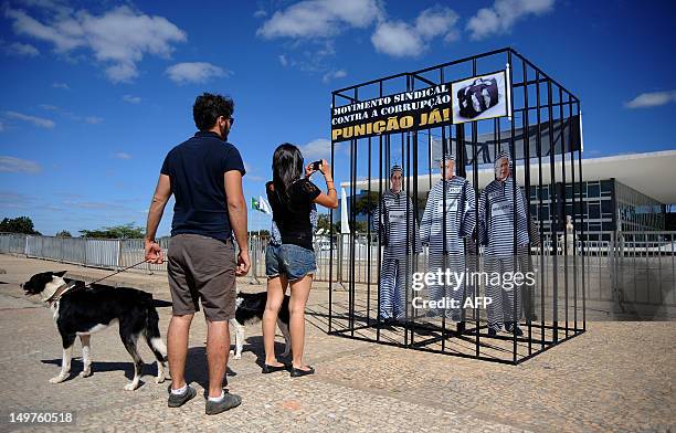 Woman takes pictures of a cell with images of some of defendants in a trial, displayed in front of the Supreme Court building, where the trial known...