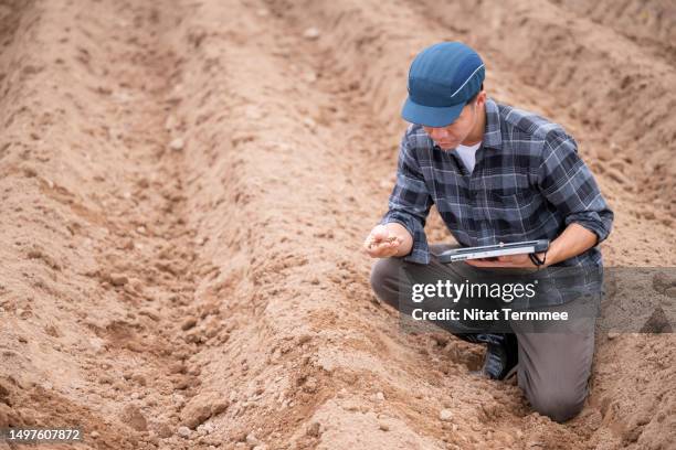 agriculture and sustainability to securing your future. high angle view of a japanese geologist analyzed the color of soil on his hand to compare with centralized data on a tablet computer in field operation. - prélèvement à tester photos et images de collection