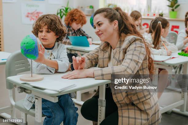 schoolboy and female teacher discussing  cross-section of planet earth diy model in classroom - geology student stock pictures, royalty-free photos & images