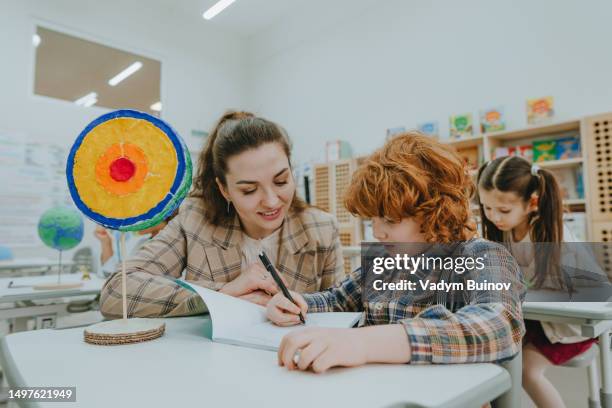 schoolboy and female teacher discussing  cross-section of planet earth diy model in classroom - geology student stock pictures, royalty-free photos & images