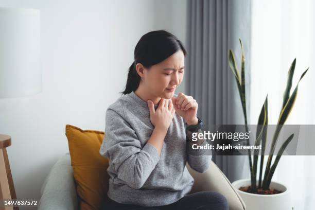 asian woman was sick with fever having sore throat sitting on armchair in living room at home. - woman cough stock pictures, royalty-free photos & images