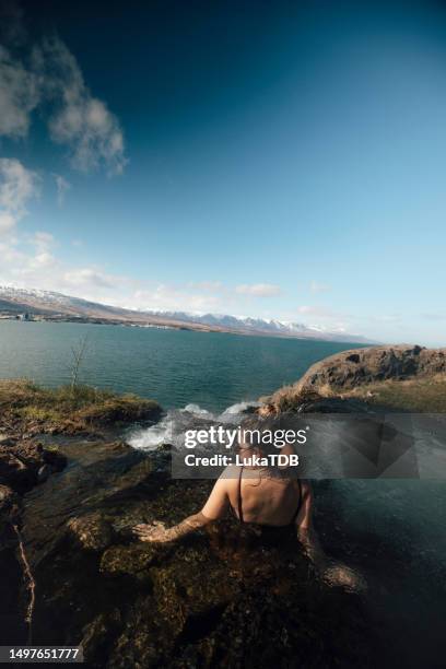 eine sorglose frau genießt es, in einer heißen quelle im freien zu schwimmen und den blick auf die herrliche natur zu genießen. island - akureyri iceland stock-fotos und bilder