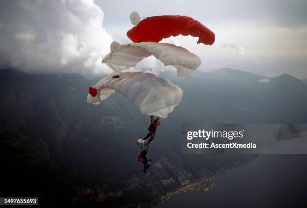 skydive athletes perform above swiss mountain landscape - aerial stunts flying stock pictures, royalty-free photos & images