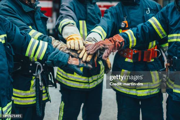 firefighters with hands stacked - brandweerwagen stockfoto's en -beelden