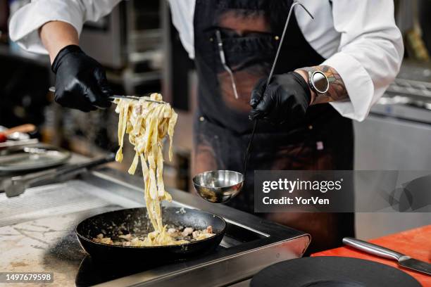 professional male chef preparing pasta in commercial kitchen - carbonara stock pictures, royalty-free photos & images