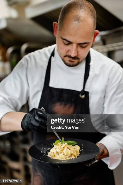 chef concentré finissant un plat de pâtes carbonara dans la cuisine du restaurant - accompagnement professionnel photos et images de collection