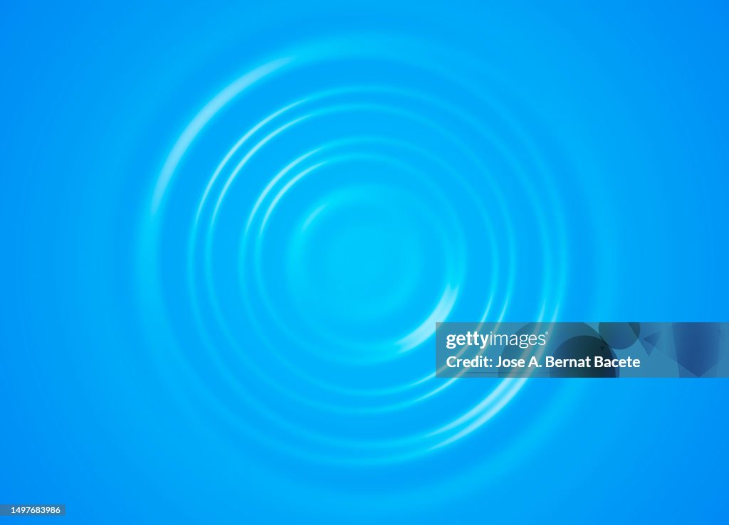 Concentric water waves produced by a drop on a blue background.