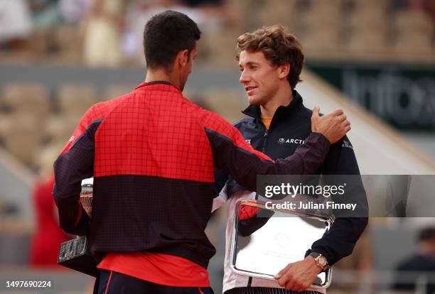 Novak Djokovic of Serbia shakes hands with Casper Ruud of Norway as they hold their winners and runners up trophies after the Men's Singles Final...