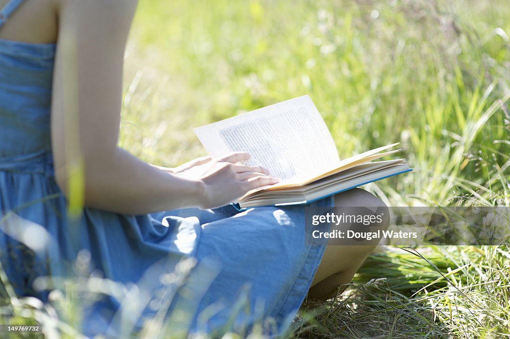 Close up of woman reading book in countryside.