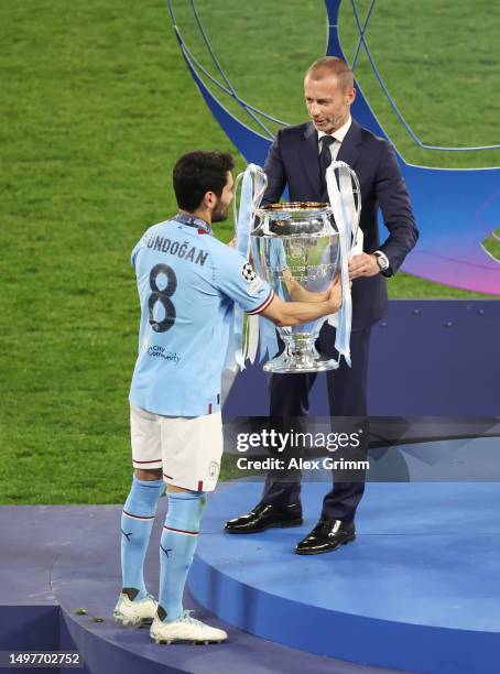 Ilkay Guendogan of Manchester City is presented with the UEFA Champions League trophy from Aleksander Ceferin, President of UEFA after the team's...