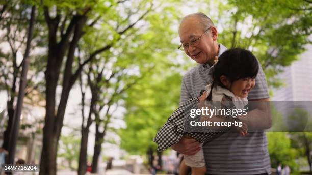 grandfather playing with her granddaughter in public park - human limb stock pictures, royalty-free photos & images