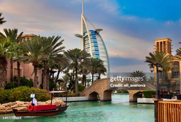 luxury boat cruise on traditional arab abra skiff on beautiful of madinat jumeirah canals with view to famous burj al arab hotel. - dubai water canal stock pictures, royalty-free photos & images