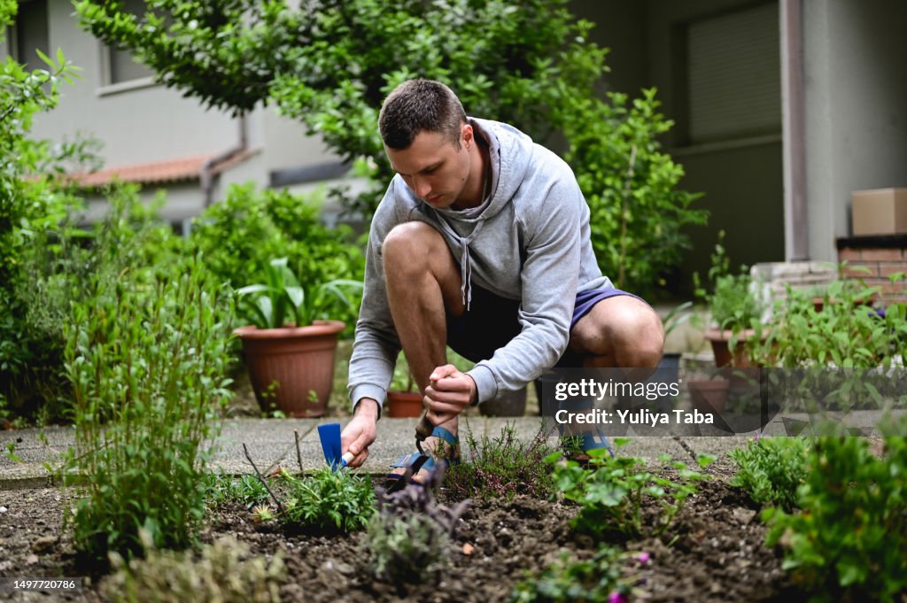 Young man working on a back yard in a garden.