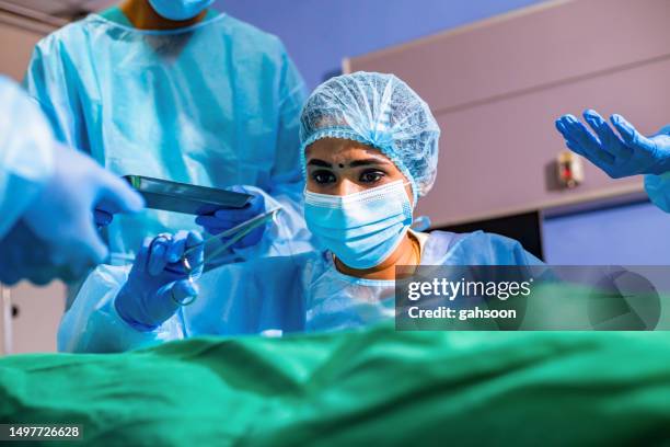 surgical suturing needle and thread being held by surgeon - operatiegewaad stockfoto's en -beelden