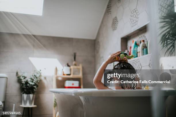 a child enjoys a warm bath in a domestic bathroom - free standing bath stock pictures, royalty-free photos & images