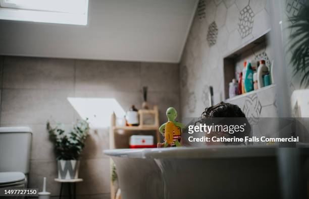 a child enjoys a warm bath in a domestic bathroom - free standing bath stock pictures, royalty-free photos & images