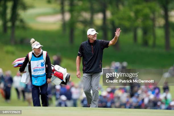 Steve Stricker of United States waves to the crowd as he walks with his caddie and wife Nicki Stricker on the 18th fairway during the final round of...