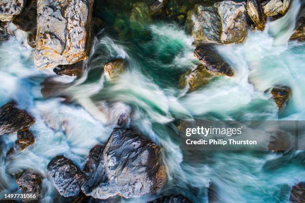 direkt oben mit blick auf den rauschenden fluss aus der schneeschmelze in den bergen - spring flowing water stock-fotos und bilder