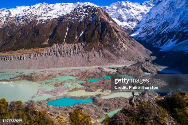nature scene of man looking out over multi-coloured moraine landscape with bright blue glacial melt pools in new zealand - new zealand volcano stock pictures, royalty-free photos & images