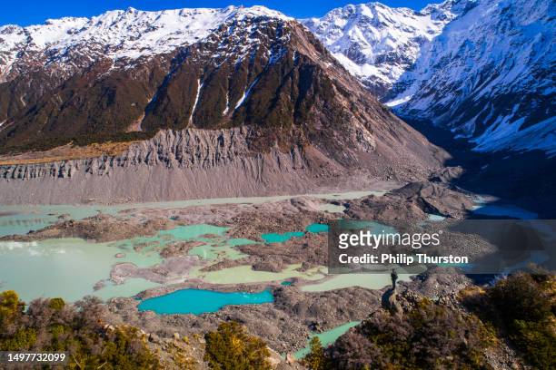 nature scene of man looking out over multi-coloured moraine landscape with bright blue glacial melt pools in new zealand - new zealand volcano 個照片及圖片檔