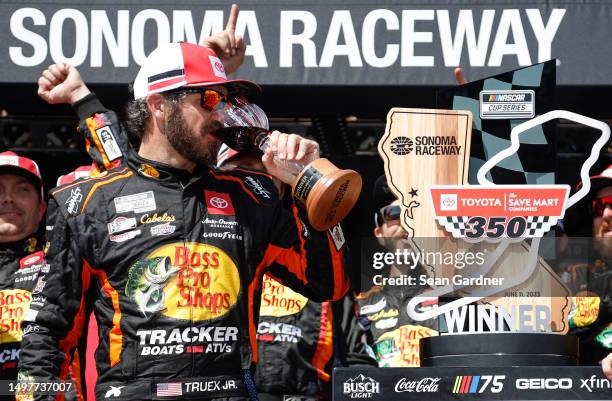 Martin Truex Jr., driver of the Bass Pro Shops Toyota, drinks wine in victory lane after winning the NASCAR Cup Series Toyota / Save Mart 350 at...