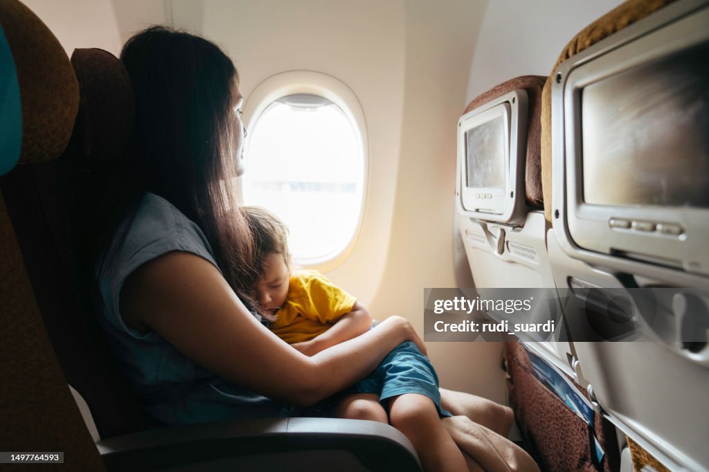 Mother holding baby son on airplane