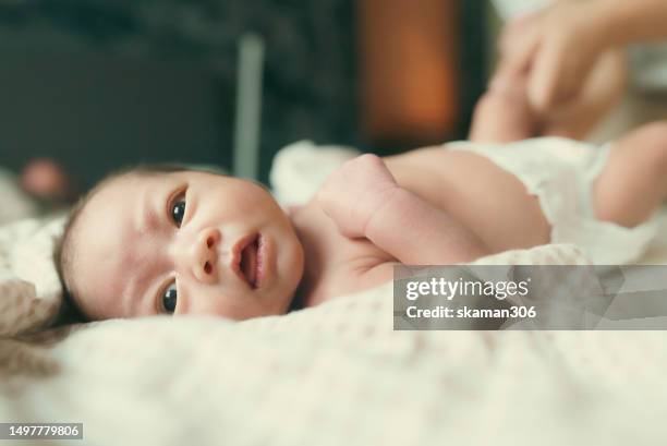 facial expression negative emotion asian newborn baby crying and lying down on the bed  during  mother changing cloth and baby diaper - black premature babies stock pictures, royalty-free photos & images