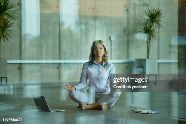 relaxed businesswoman meditating on the floor in the office. - office yoga stock pictures, royalty-free photos & images