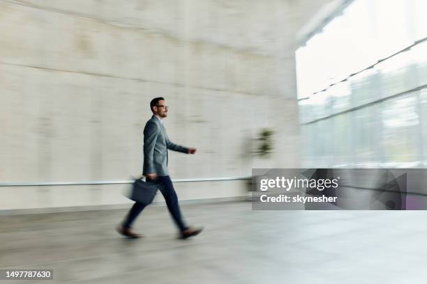 smiling businessman walking in a hallway in blurred motion. - smart casual walking stock pictures, royalty-free photos & images