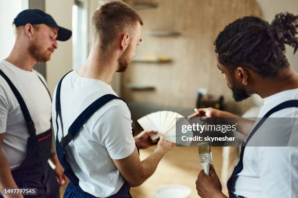 team of manual workers choosing colors in the apartment. - decorating stock pictures, royalty-free photos & images