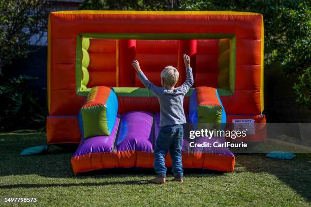 ein kleiner junge spielt zu seinem geburtstag auf einer hüpfburg. - inflatable playground stock-fotos und bilder