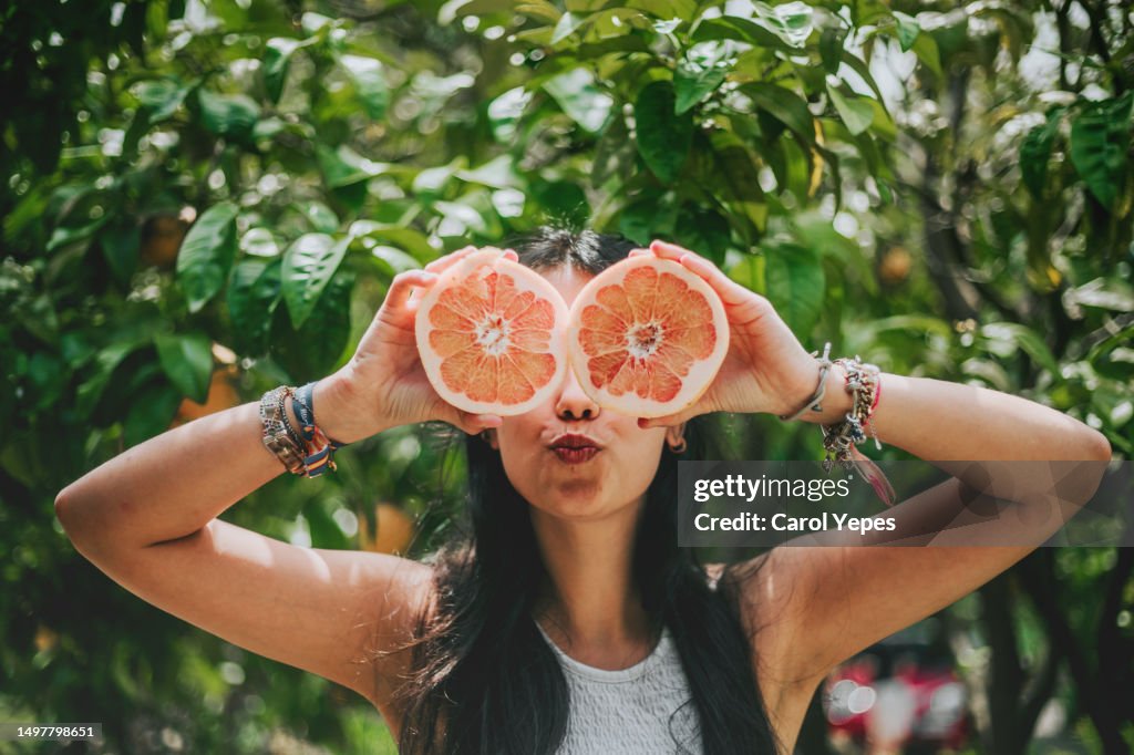 Pretty latina with oranges in front of eyes