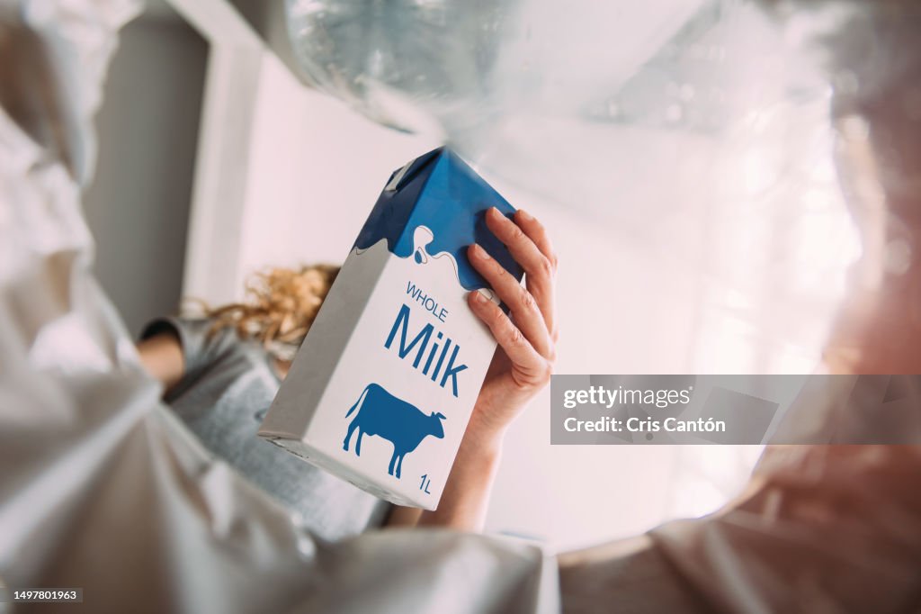 Hand throwing milk tetra brik into plastic recycling bin