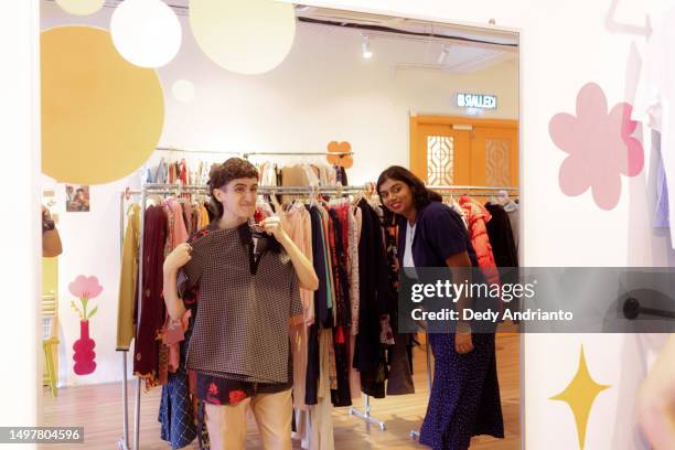 small group of multicultural friends trying shopping at local fashion thrift shop - thrift shopping stock pictures, royalty-free photos & images