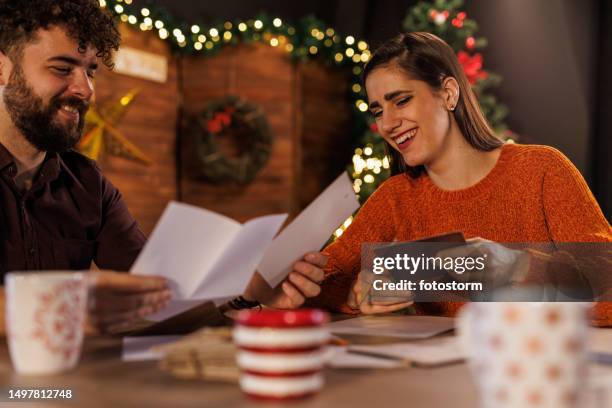 young couple having fun writing christmas cards and letters together - christmas cards stock pictures, royalty-free photos & images