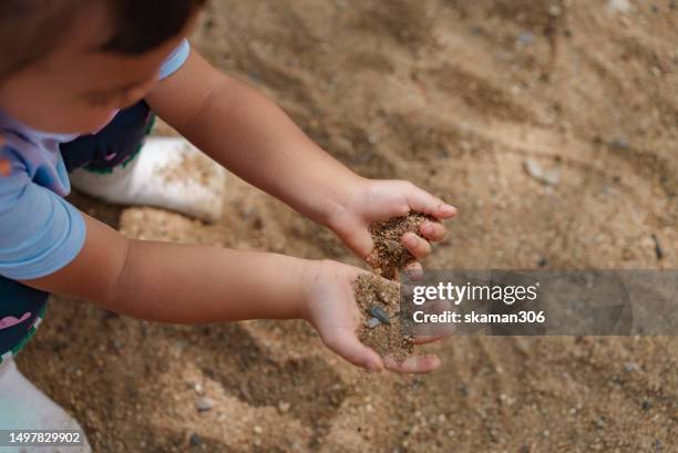 happy weekend activity asian toddler enjoy playing sandbox on the playground at public park - zandbak stockfoto's en -beelden