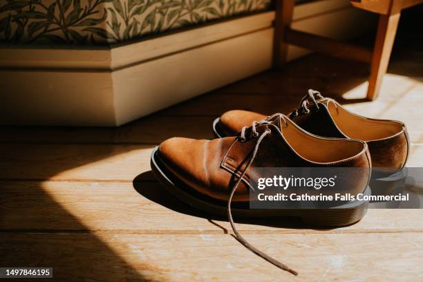 simple, conceptual image of a pair of brown brogues, illuminated by sunlight - bruine schoen stockfoto's en -beelden