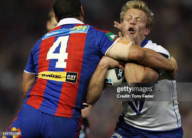 James Graham of the Bulldogs is tackled by Timana Tahu of the Newcastle Knights during the Round 22 NRL match between the Newcastle Knights and the...