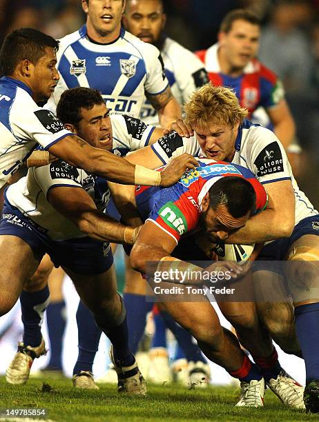 Timana Tahu of the Newcastle Knights is tackled by a group of Bulldogs players during the Round 22 NRL match between the Newcastle Knights and the...