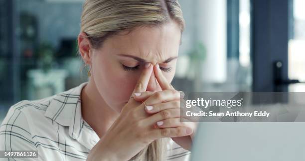 a business woman using a laptop with stress and a headache in a modern office. a businesswoman working online and feeling tired with burnout at her desk - banging your head against a wall stock pictures, royalty-free photos & images